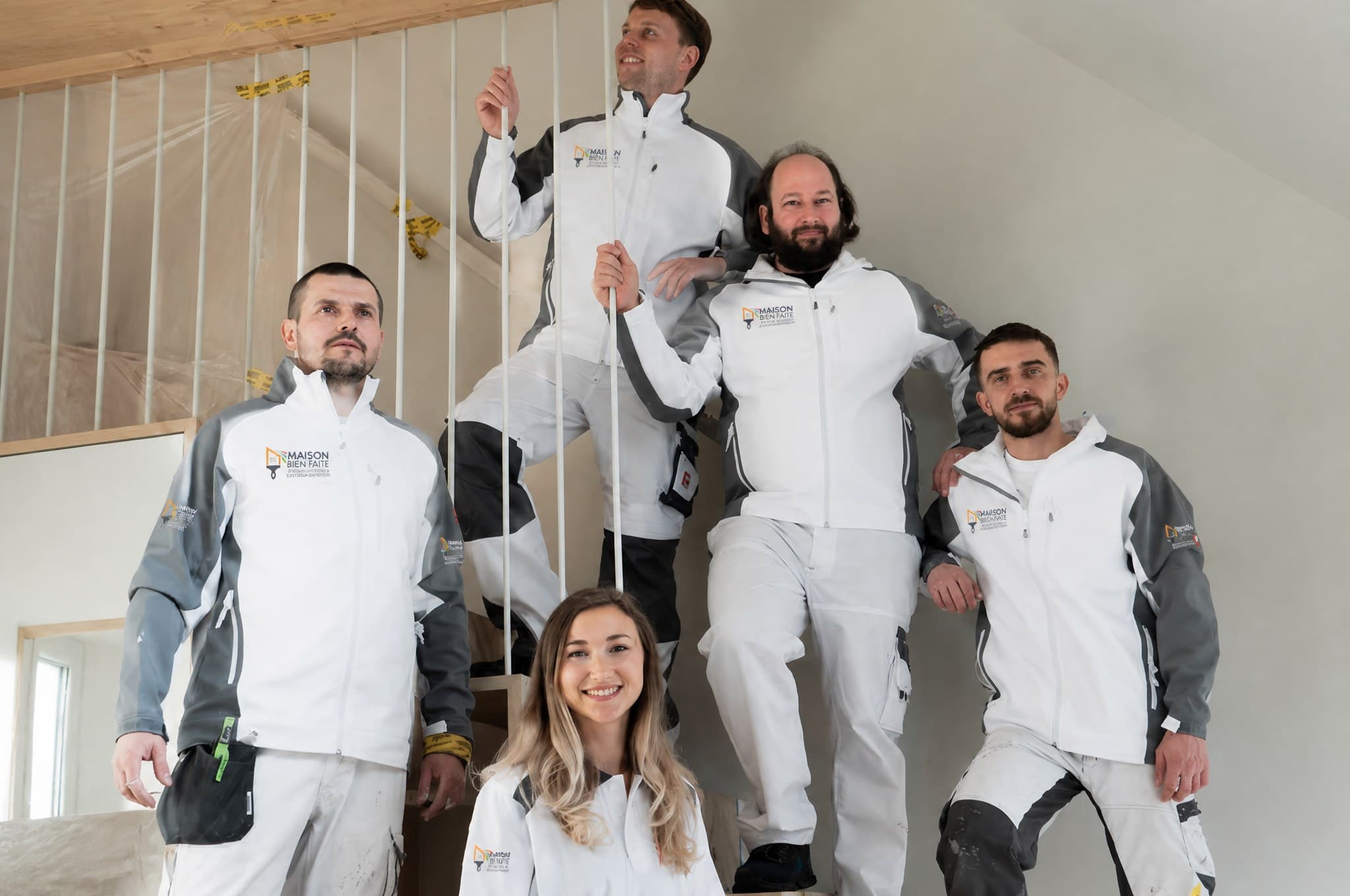 L'équipe Maison Bien Faite en uniforme dans l'escalier d'un chantier intérieur